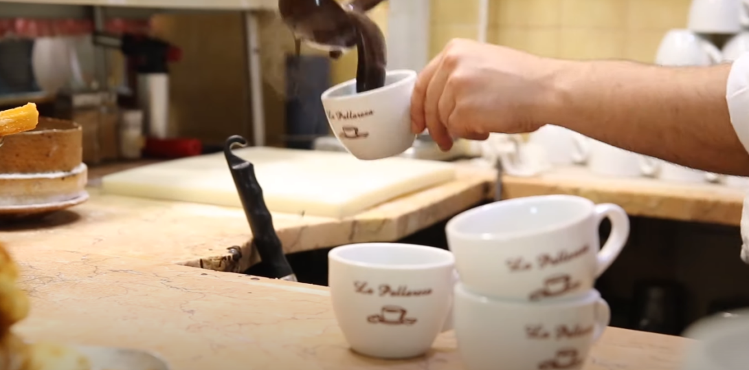 A hand pouring chocolate onto a mug