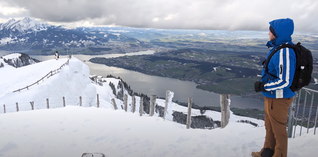 A man atop a snow-covered mountain, showcasing the view below