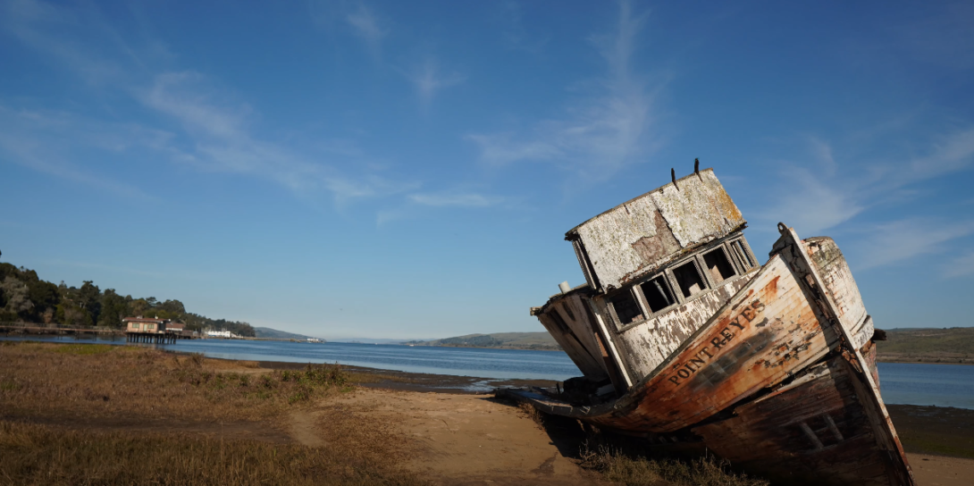 A lake with dry land and a non-functional old boat