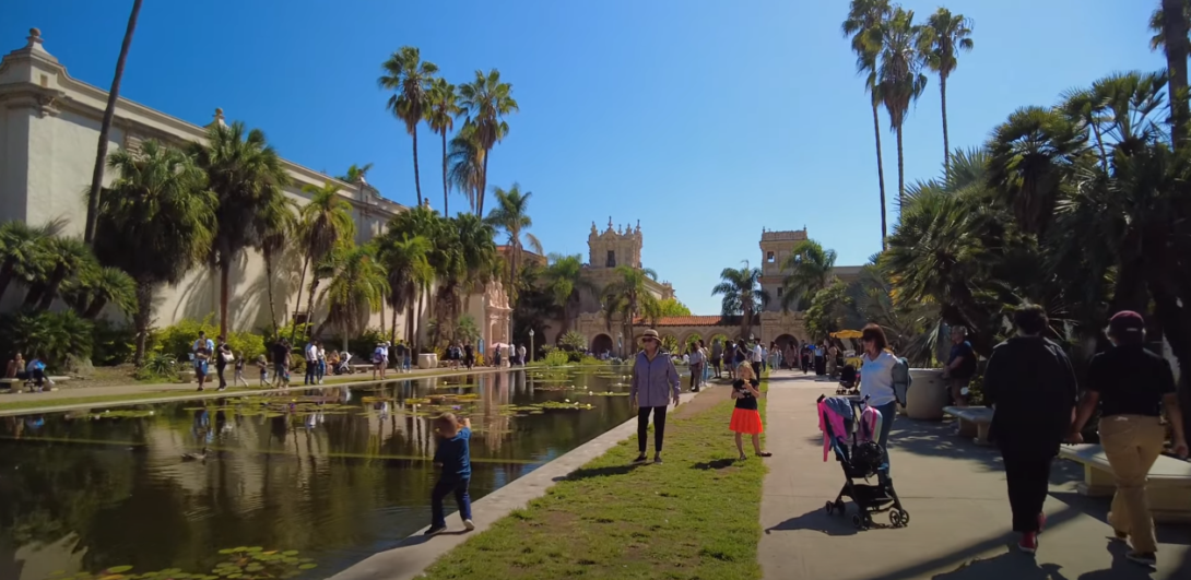 Individuals walking at the park with a central pond