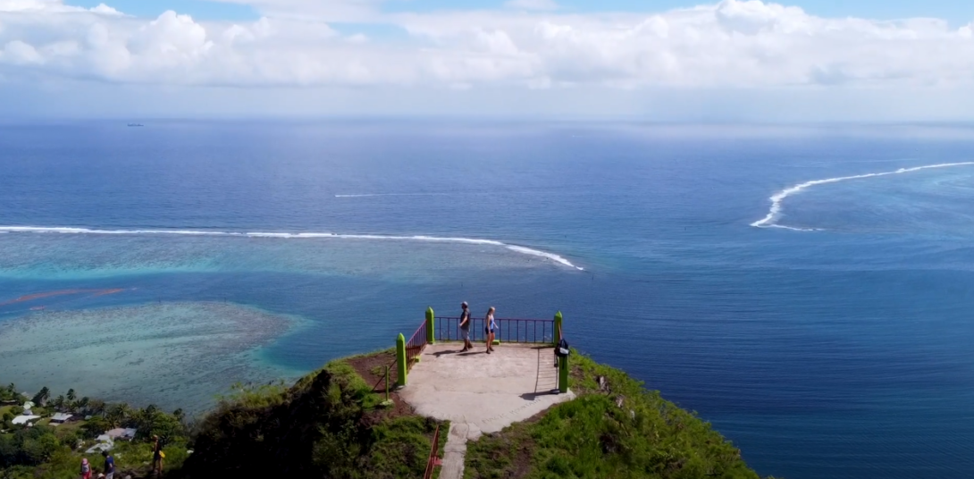 Two individuals on a mountaintop overlooking a body of water