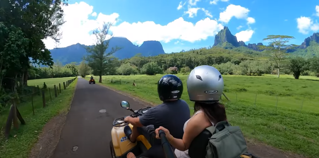 Two people on an ATV in a lush environment