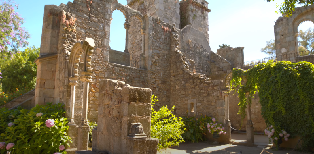 Unfinished historic structure surrounded by plants and flowers