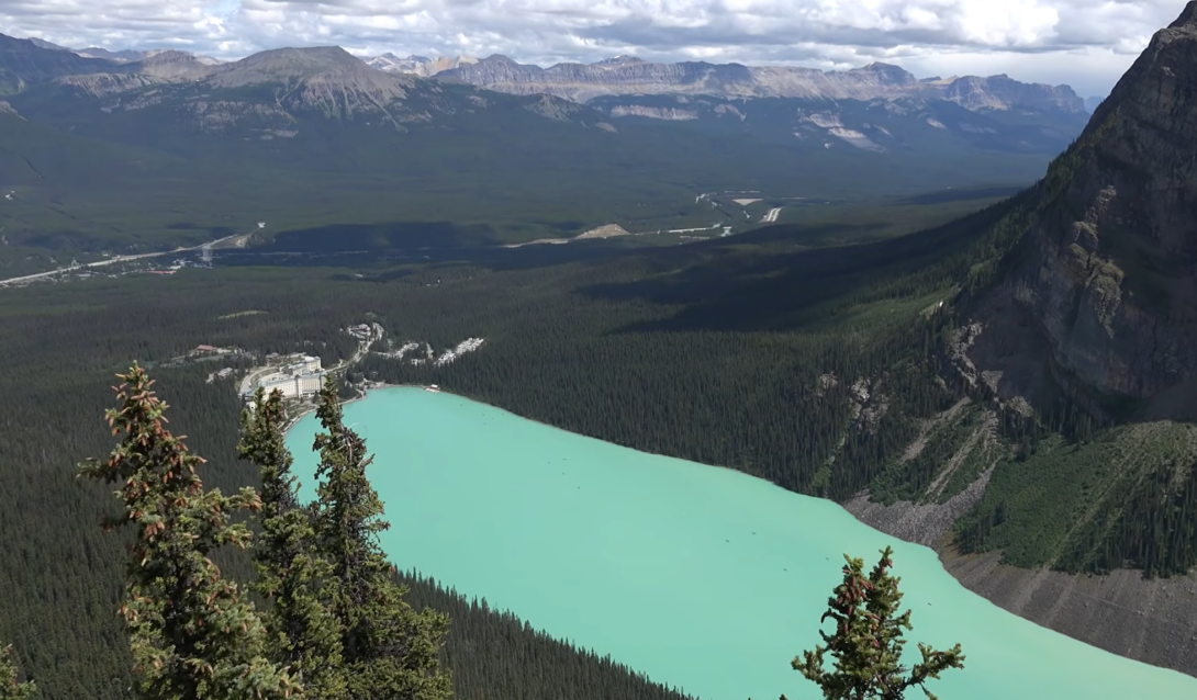 lake agnes between mountains and trees, the landscape of hills far away