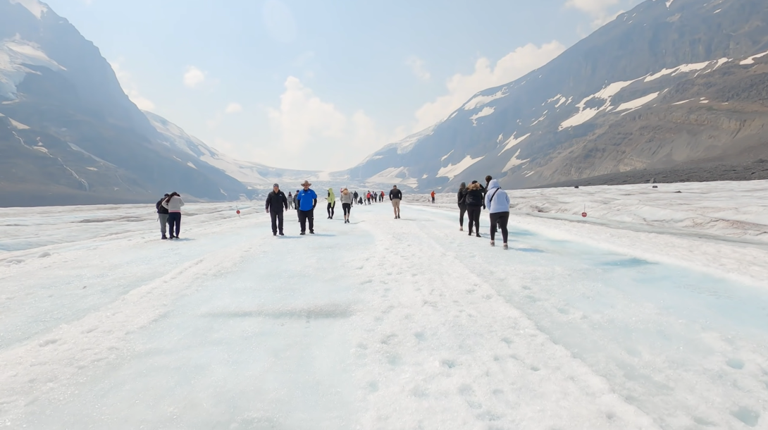 Athabasca Glacier - iced mountains and people walking on ice