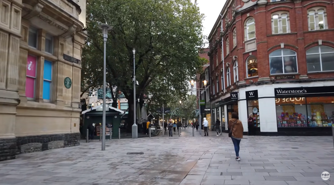 woman walking on the street, Waterstones shop, street lights, and trees