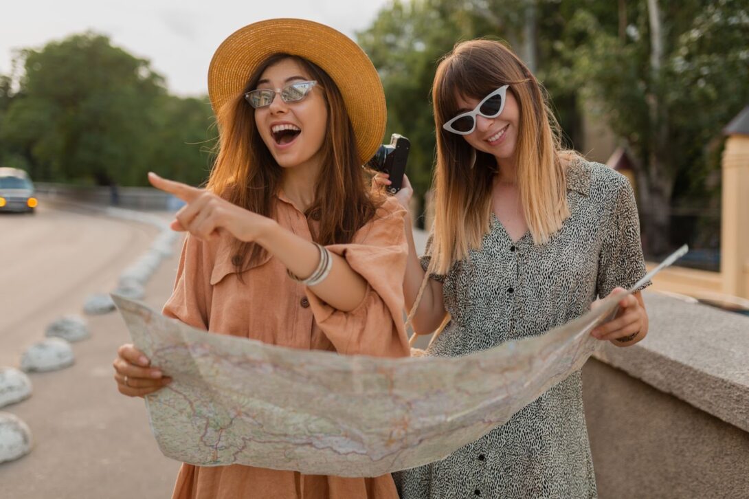 Young women looking on map and traveling together