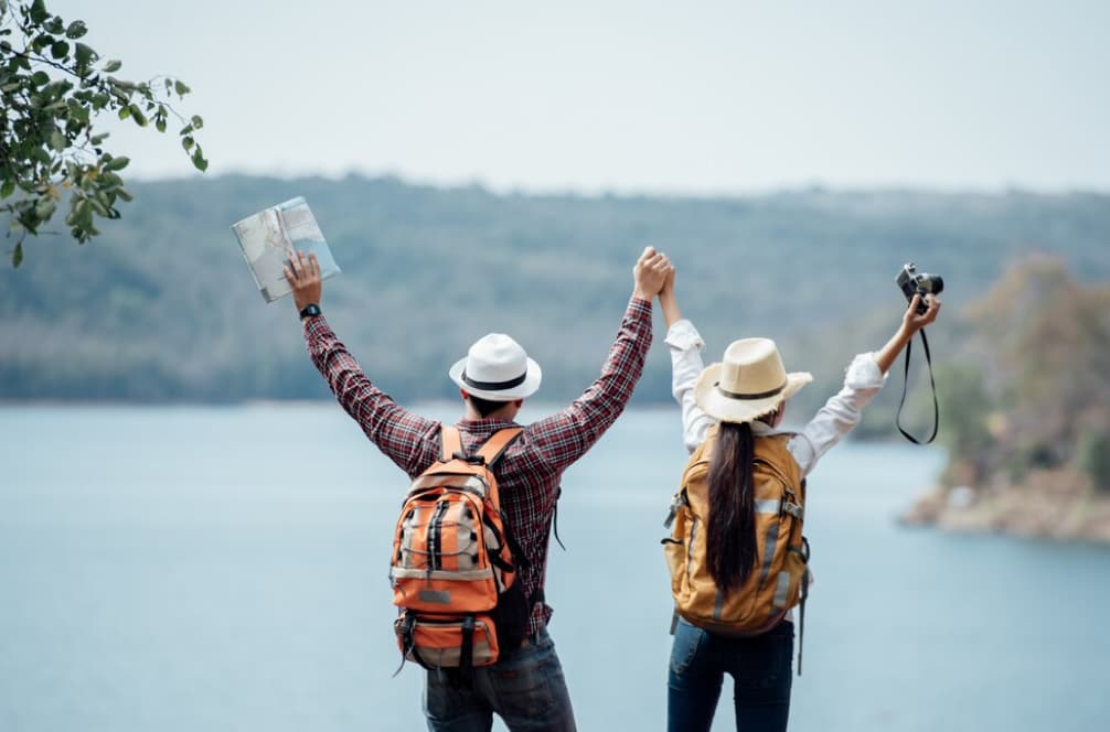 Two travelers celebrate their adventure beside a lake