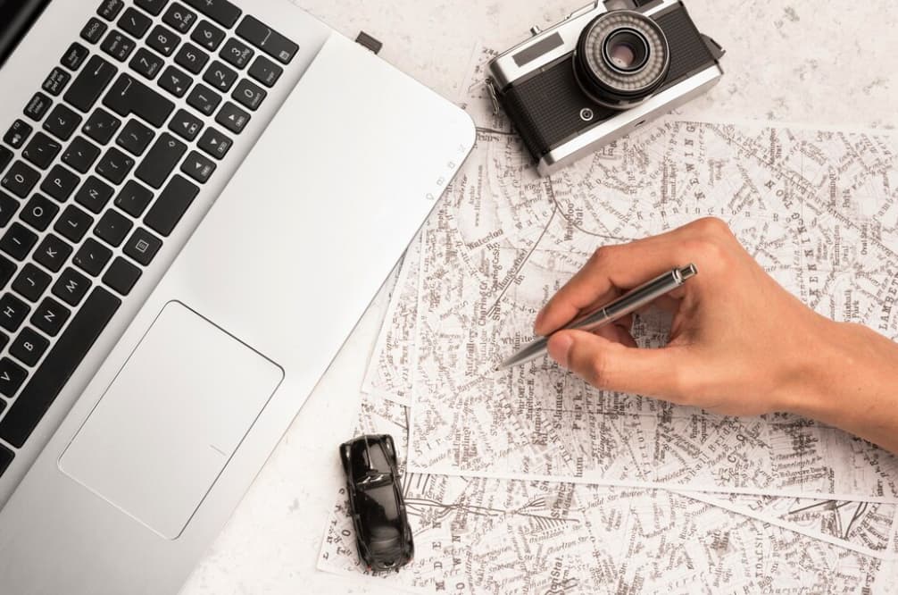 Planning a trip with a map and laptop on a marble surface